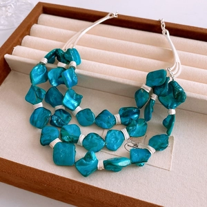 Detail of bohemian three-layer necklace with blue geometric shell beads in a gift box