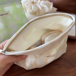 Close-up of beige polka dot pleated makeup bag showing interior storage for cosmetics