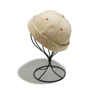 Detail of khaki paisley docker hat featuring white patterns and orange embroidered eyelets