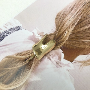 Detailed close-up of a polished gold irregular alloy hair clip with metallic finish