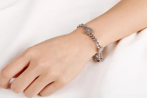 Silver four-leaf clover clover bracelet featuring a classic curb chain on a model's wrist