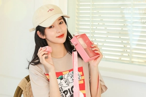 Asian model wearing a pink flat rectangular water bottle with an adjustable strap