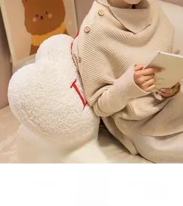 Close-up of soft plush heart pillow with red letter I embroidery on white wool fabric