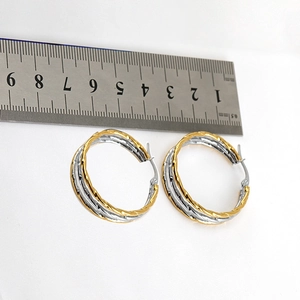 Detailed size measurement of 35mm twisted gold and silver hoop earrings with a ruler
