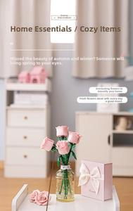 Pink building block rose bouquet in glass vase next to a romantic gift box on a white table