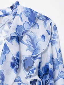 Close-up of blue floral chiffon fabric with ruffled details and pleated texture