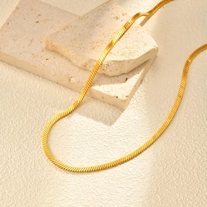 Élégant collier chaîne serpent plate dorée double couche sur blocs de pierre beige