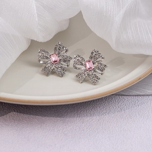 Macro shot of silver bow earrings with sparkling white crystals and a pink gemstone core