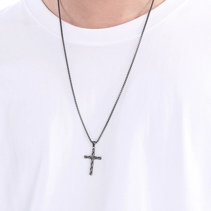 Detail of grey stainless steel cross pendant on a box chain worn by a male model