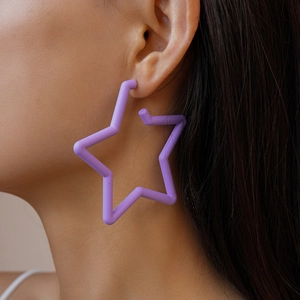 Gros plan d'un modèle portant de grandes boucles d'oreilles étoiles violettes mates
