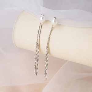 Detailed macro view of long tassel earrings featuring sparkling rhinestones and white pearls