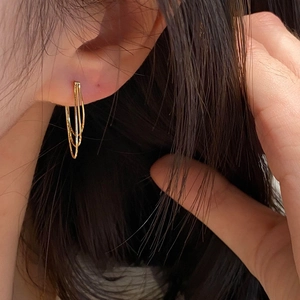 Detailed close-up of golden multi-layer spiral hoop earrings worn on a female model