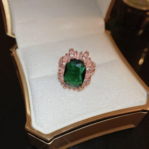 Elegant emerald-cut green zircon ring in rose gold setting with shimmering halo crystals