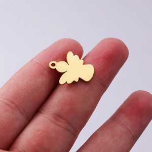 Polished gold angel wing pendant charm in stainless steel held between fingers