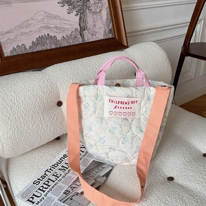 Détail du sac cabas matelassé à fleurs avec poignées roses et bandoulière orange