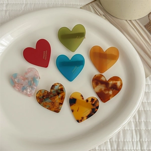 Collection of colorful acetate heart hair clips with France Handmade lettering in a tray