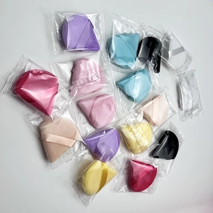 Detailed view of multiple colored triangular makeup puffs in individual plastic packaging
