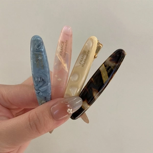 Détail de quatre barrettes en acétate faites à la main aux motifs marbrés et écailles