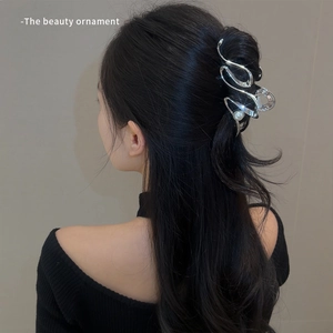 Silver metallic streamlined shark hair claw clip with pearl detail on woman hair