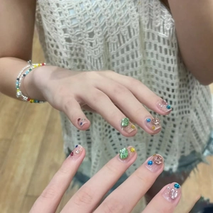 Macro detail of colorful crystal rhinestones and green gems on handmade press-on nails