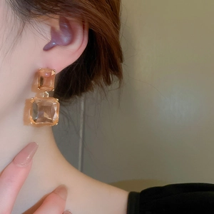 Detail of amber geometric crystal earrings with golden claw setting on model