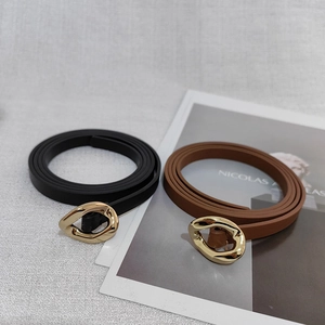 Detail of black and brown leather belts with irregular gold molten-style metal buckles