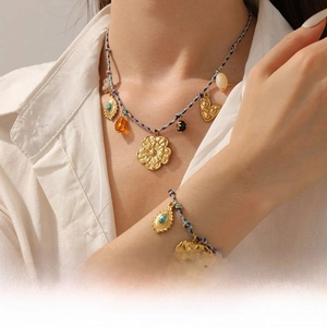 Detail of colorful woven chain necklace with bohemian gold pendants on a model