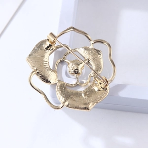 Macro shot of gold hollow rose brooch showing back safety pin and metal clasp detail