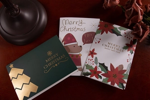 Detail of premium gold foiled Christmas cards with festive greetings on a dark wooden table