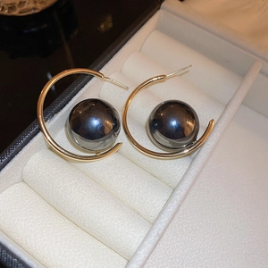 Detail of vintage C-shape gold earrings featuring a large polished black bead centerpiece