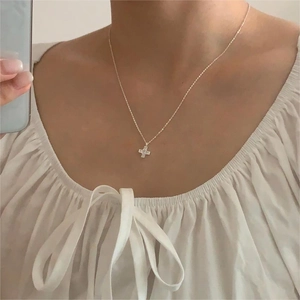 Detail of minimalist 925 sterling silver cross pendant with sparkling zircon on model neck