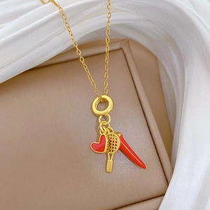 Detailed close-up of golden necklace with red heart, tennis racket and chili charms