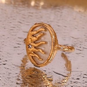 Macro view of gold-plated celestial ring with shell inlay and sun star relief detail