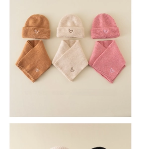Detail of knitted baby hat and scarf sets with heart embroidery in autumn colors