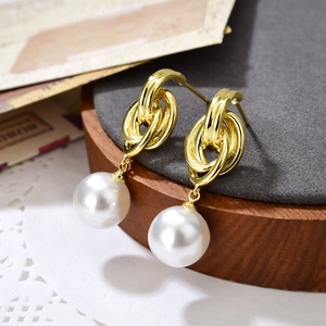 Elegante goldene Metall-Ohrringe mit großen weißen Perlen auf einem Vintage-Hintergrund