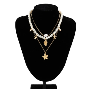 Close-up of layered necklace with faux pearls and gold starfish shell charms