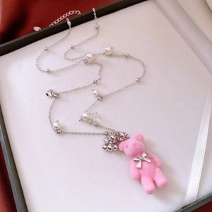 Close-up of pink flocked bear pendant with pearl fringe and bow on elegant sweater necklace
