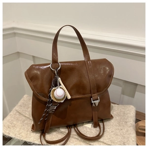 Dettaglio dello zaino vintage marrone con fibbie in metallo e ciondolo da baseball