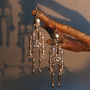 Detail of gold skeleton earrings hanging on a branch with dramatic shadow lighting