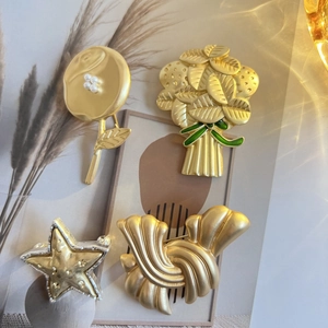 Broches vintage en or mat avec perles et détails de feuilles en émail vert en vue à plat