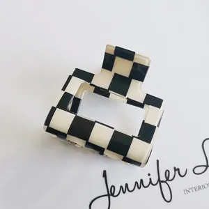 Detail shot of a minimalist black and white checkerboard hair claw clip with a glossy finish
