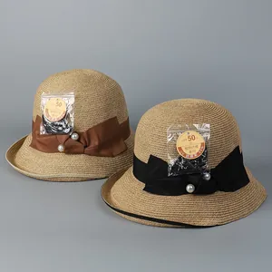 Detail of straw sun hats with UPF 50+ protection, pearl bow accents, and woven texture
