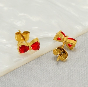 Macro shot of red heart-shaped zircon bow earrings with 18K gold-plated metal borders