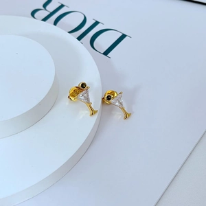 Detail of gold-plated cocktail glass earrings with zircon inlay on a white pedestal