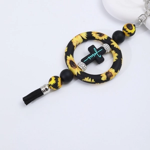 Close-up of silicone cross pendant with sunflower beads and stylish black tassel detail