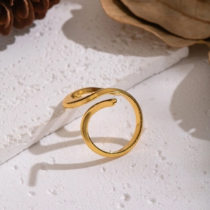 Detail of adjustable spiral gold ring on stone base with natural pinecone background