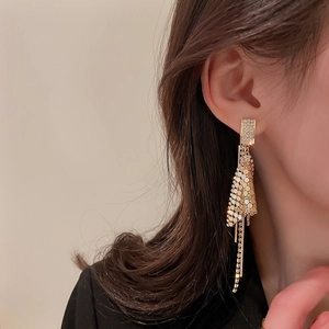 Detail showing long gold tassel earrings with sequins and rhinestones on a female model