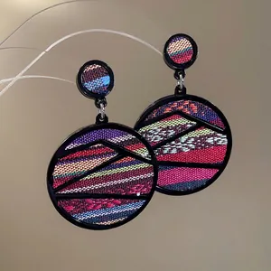 Ethnic geometric drop earrings featuring colorful woven fabric inside black round hoops
