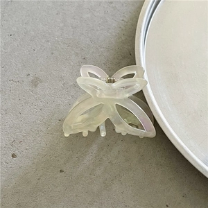 Close-up of translucent beige butterfly hair claw clip with golden metal spring