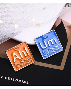 Détail des pin's en émail avec des motifs humoristiques sur le tableau périodique